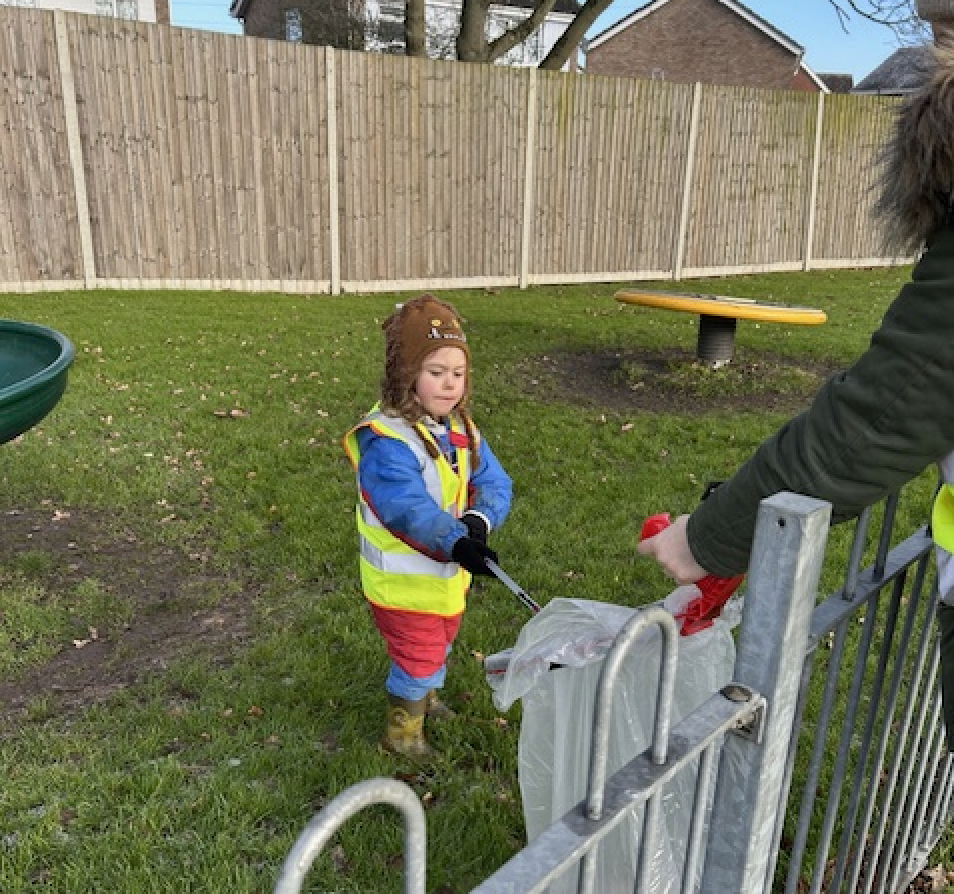 A young child wearing a high-vis and litter-picking